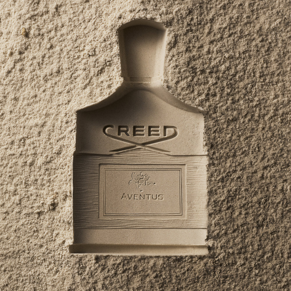 Creed Aventus flacon photographed against a plaster wall