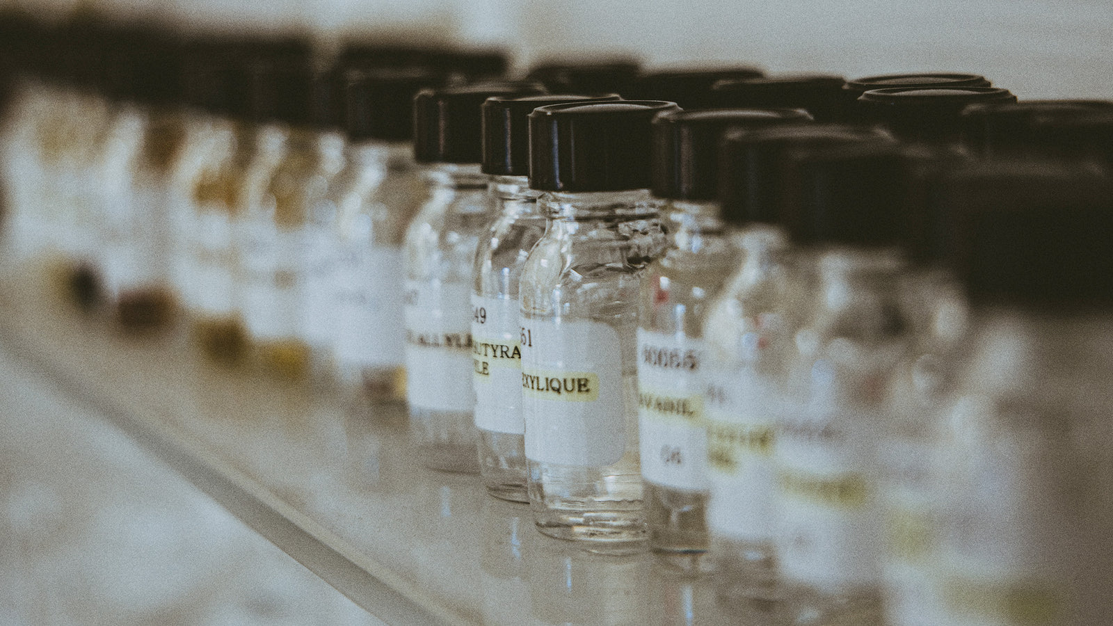A row of Creed fragrance flacons arranged on a stone ledge in daylight